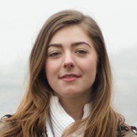 Portrait of a person with long brown hair and a white scarf against a light background